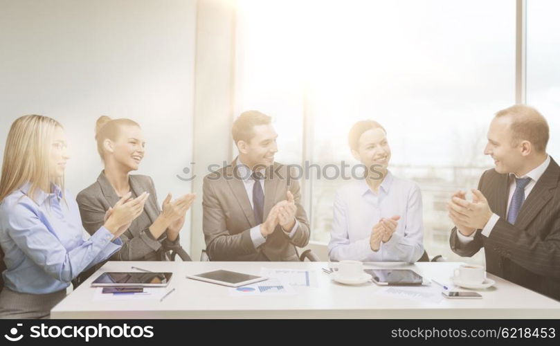 business, technology and office concept - happy business team with laptop computers, documents and coffee clapping hand