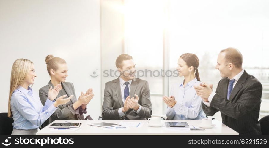 business, technology and office concept - happy business team with laptop computers, documents and coffee clapping hand