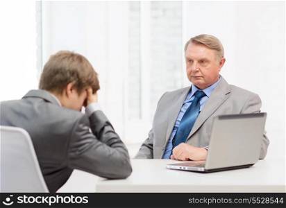 business, technology and office concept - older man and young man having argument in office