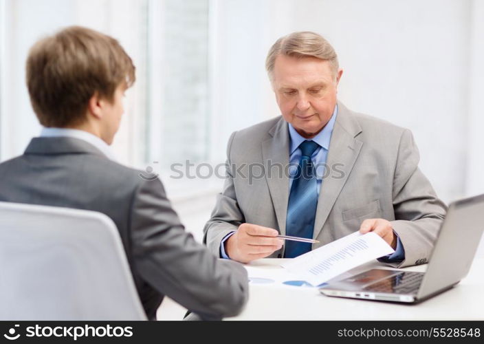 business, technology and office concept - older man and young man having meeting in office