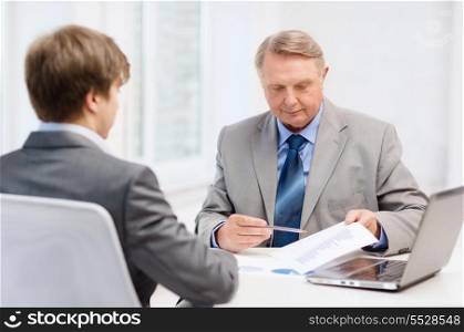 business, technology and office concept - older man and young man having meeting in office