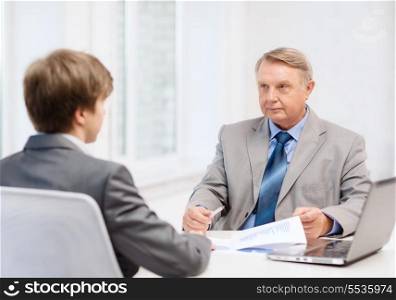 business, technology and office concept - older man and young man having meeting in office