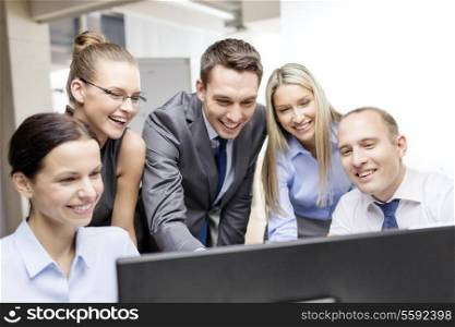 business, technology and office concept - smiling business team with computer monitor having discussion in office