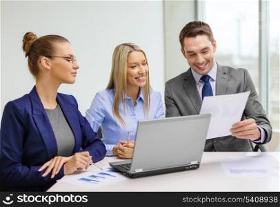 business, technology and office concept - smiling business team with laptop computers and documents having discussion in office