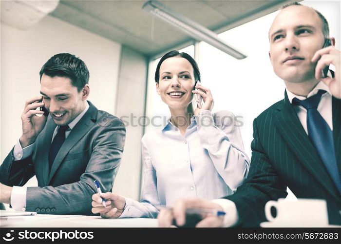 business, technology and office concept - smiling business team with smartphones making calls in office