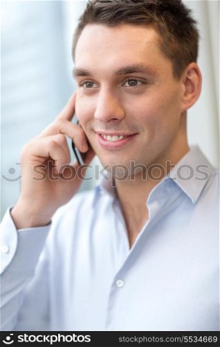 business, technology and office concept - smiling businessman with smartphone in office