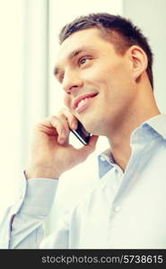 business, technology and office concept - smiling businessman with smartphone in office