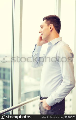 business, technology and office concept - smiling businessman with smartphone in office