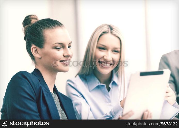 business, technology and office concept - smiling businesswomen with tablet pc computers having discussion in office