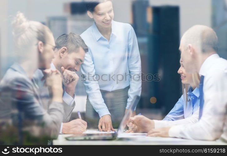 business, technology and office concept - smiling female boss talking to business team