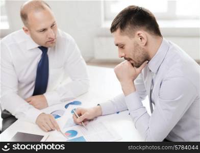 business, technology and office concept - two businessmen with tablet pc computer and papers having discussion in office