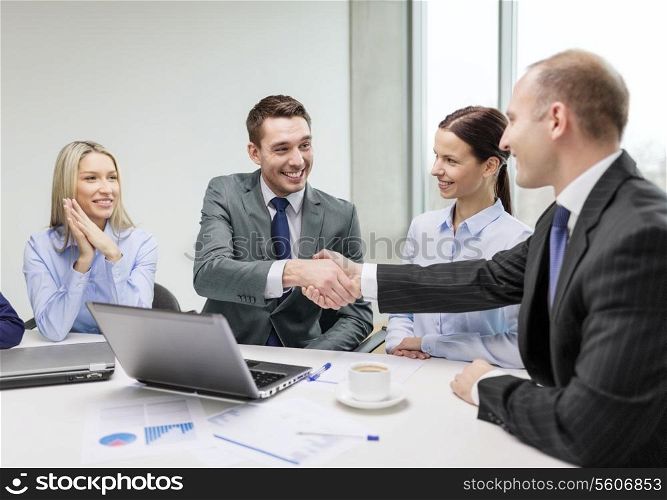 business, technology and office concept - two smiling businessman shaking hands in office