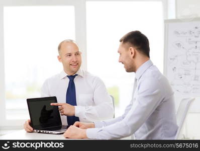 business, technology and office concept - two smiling businessmen with laptop having presentation in office