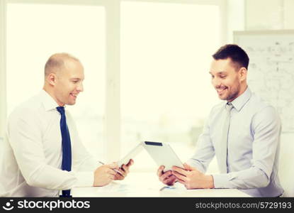 business, technology and office concept - two smiling businessmen with tablet pc computers and files in office