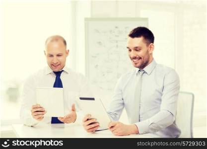 business, technology and office concept - two smiling businessmen with tablet pc computers in office