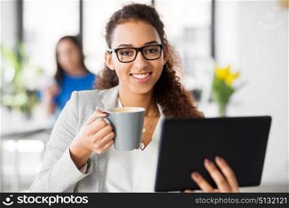 business, technology and people concept - african american businesswoman with tablet pc computer drinking coffee at office. businesswoman with tablet pc and coffee at office. businesswoman with tablet pc and coffee at office