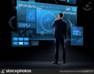business, technology and people concept - businessman in suit looking at virtual screen over black background from back. businessman looking at virtual screen from back