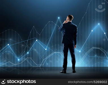 business, technology and people concept - businessman in suit looking at virtual chart over black background from back. businessman in suit from back with virtual graph