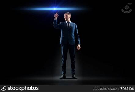 business, technology and people concept - businessman in suit pointing finger to laser light ray over black background. businessman in suit pointing finger to laser light