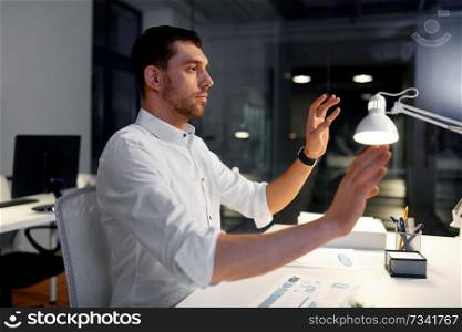business, technology and people concept - businessman using gestures at night office. businessman using gestures at night office