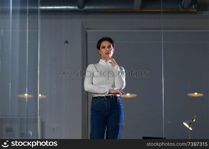 business, technology and people concept - businesswoman looking at glass wall at night office. businesswoman looks at glass wall at night office