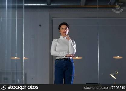 business, technology and people concept - businesswoman looking at glass wall at night office. businesswoman looks at glass wall at night office