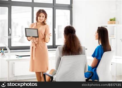 business, technology and people concept - businesswoman showing tablet pc computer to female team at office. woman showing tablet pc to business team at office. woman showing tablet pc to business team at office