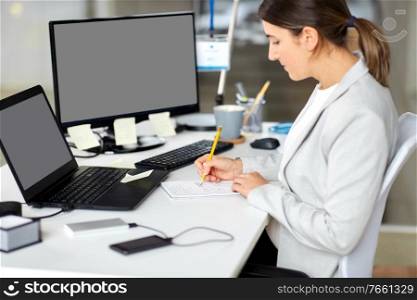 business, technology and people concept - businesswoman with notebook and laptop computer working at office. businesswoman with notebook and laptop at office