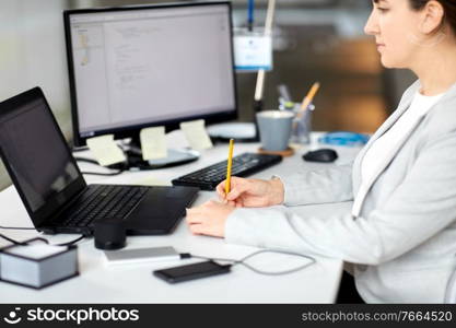 business, technology and people concept - businesswoman with notebook and laptop computer working at office. businesswoman with notebook and laptop at office