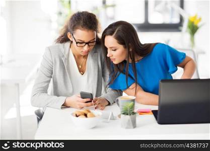 business, technology and people concept - businesswomen with smartphone and laptop computer working at office. businesswomen with smartphone working at office. businesswomen with smartphone working at office