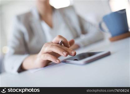 business, technology and people concept - close up of hand of businesswoman using smartphoner at office. hand of businesswoman using smartphone at office