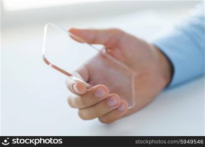 business, technology and people concept - close up of male hand holding and showing transparent smartphone at office