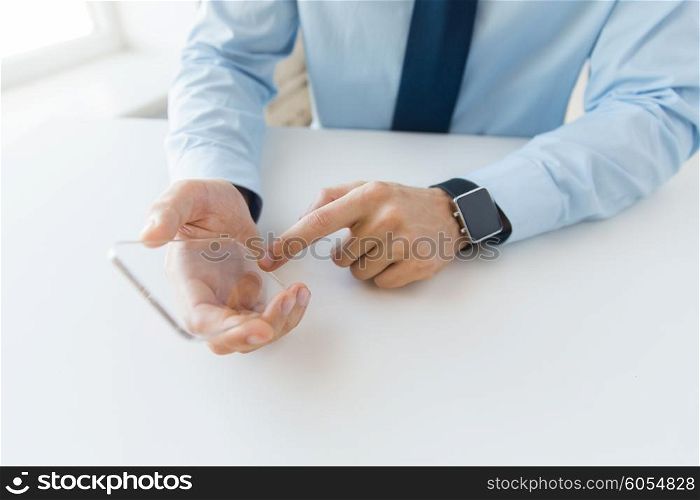 business, technology and people concept - close up of male hand holding and showing transparent smart phone and watch at office