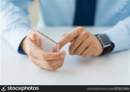 business, technology and people concept - close up of male hand holding and showing transparent smart phone and watch at office
