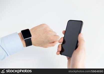 business, technology and people concept - close up of male hand holdingt smart phone and wearing watch at home