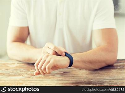 business, technology and people concept - close up of male hands with heart-rate watch at home