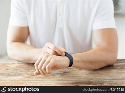 business, technology and people concept - close up of male hands with heart-rate watch at home