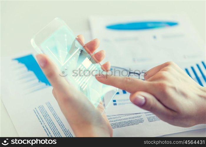 business, technology and people concept - close up of woman hand holding and showing transparent smartphone with chart on screen at office