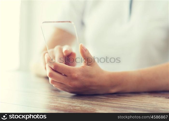 business, technology and people concept - close up of woman hand holding and showing transparent smartphone at home. close up of woman with transparent smartphone