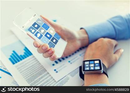 business, technology and people concept - close up of woman hand holding transparent smartphone and smartwatch with application icons on screen at office
