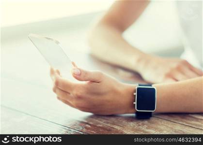 business, technology and people concept - close up of woman hand holding and showing transparent smart phone and watch at office