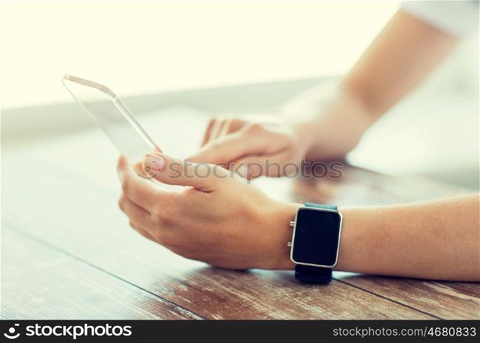 business, technology and people concept - close up of woman hand holding and showing transparent smart phone and watch at office
