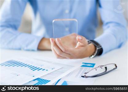 business, technology and people concept - close up of woman hand holding and showing transparent smartphone at office