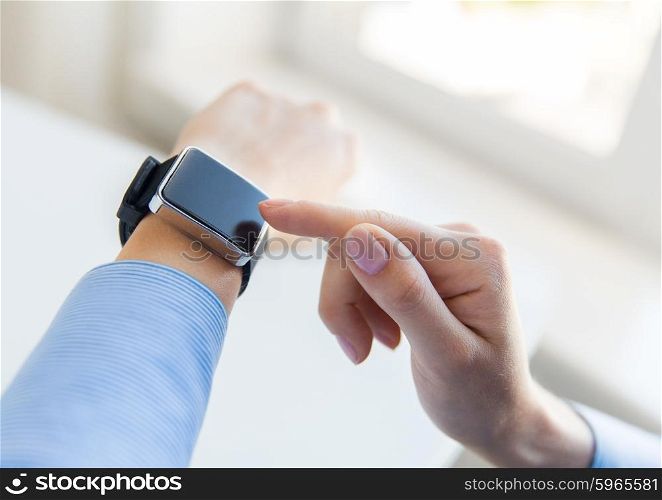 business, technology and people concept - close up of woman hands setting smart watch at office