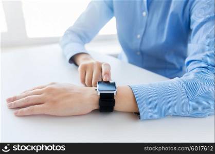business, technology and people concept - close up of woman hands setting smart watch at office