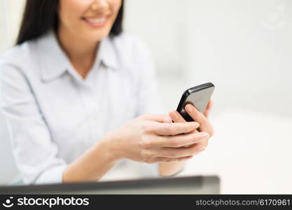 business, technology and people concept - close up of woman hands texting message on smartphone