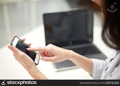 business, technology and people concept - close up of woman hands with laptop computer and smartphone texting message at office