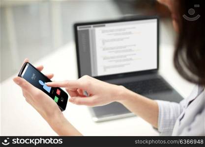 business, technology and people concept - close up of woman hands with laptop computer and smartphone at office. close up of woman with smartphone at office