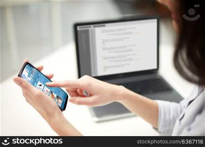 business, technology and people concept - close up of woman hands with news web page on smartphone screen at office. close up of woman with business news on smartphone