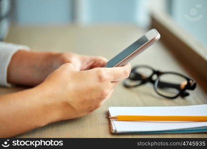 business, technology and people concept - close up of woman texting on smartphone